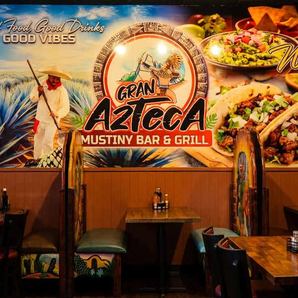 Restaurant interior with a large mural featuring Mexican food, agave plants, and the Gran Azteca logo.